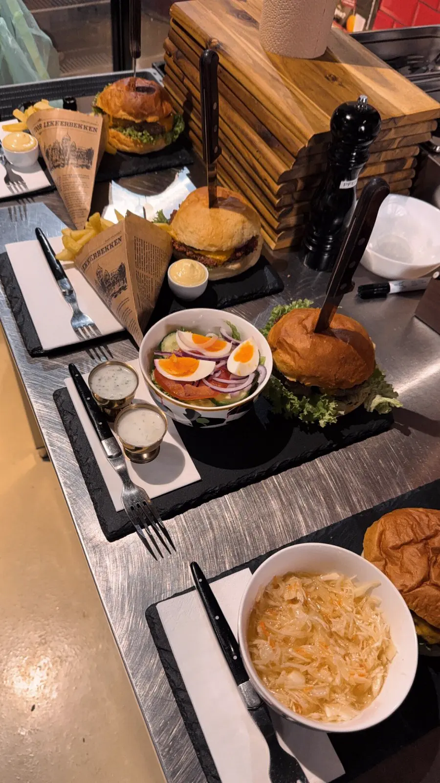 Fertige Burger mit Salat und Krautsalat auf Schieferplatten am Küchenpass