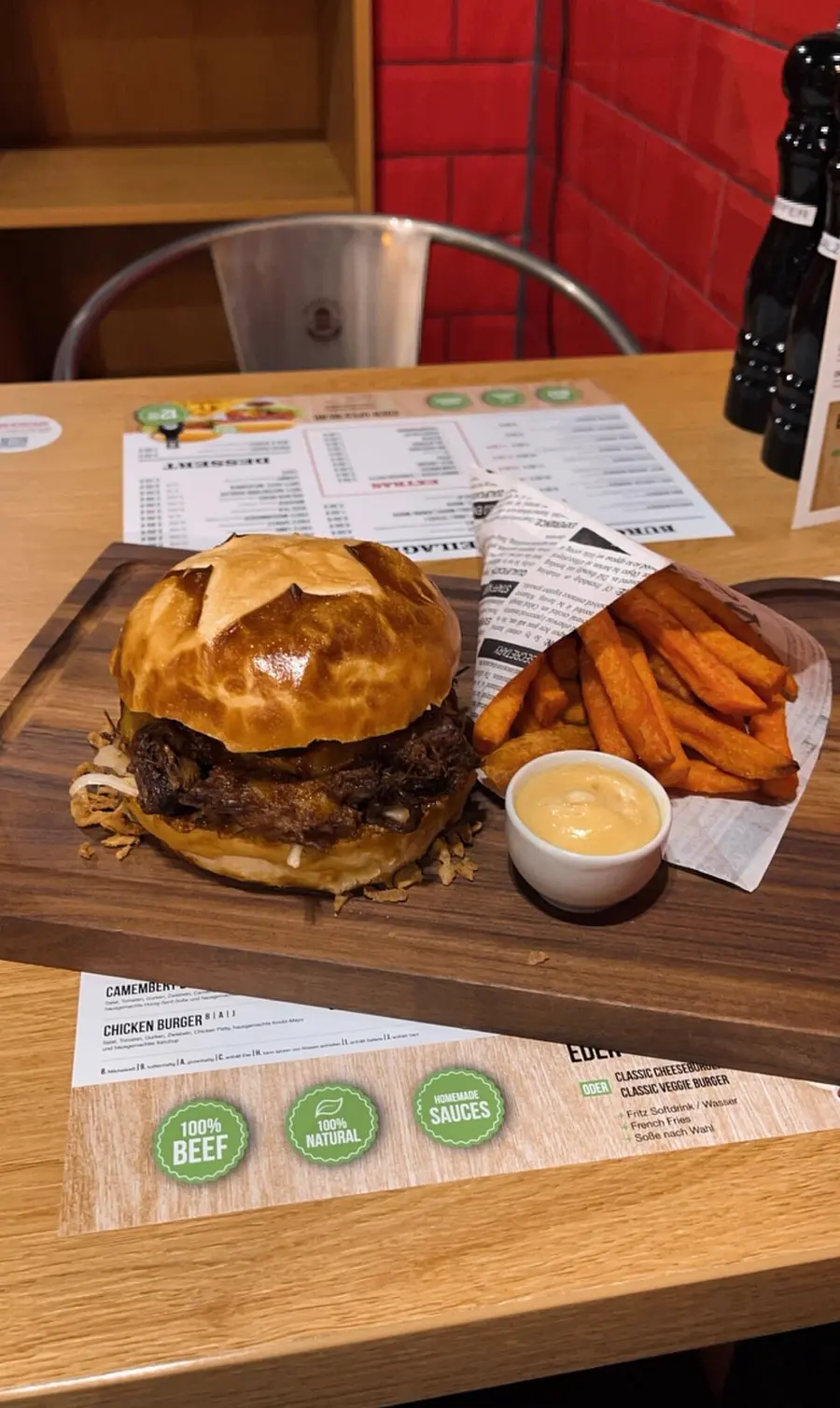 Burger mit Sweet Potato Fries und hausgemachter Soße auf einem Holzbrett